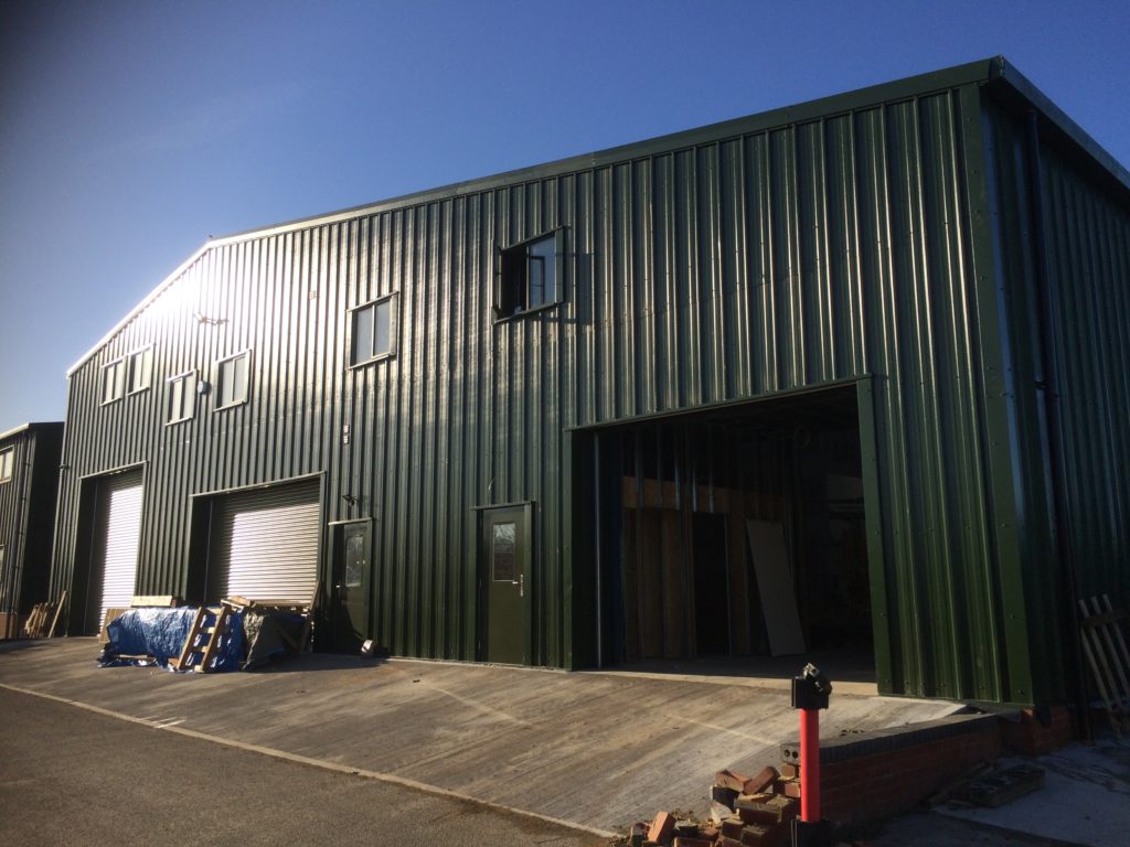 Large Juniper Green Joinery Factory & Offices set before a clear blue sky line